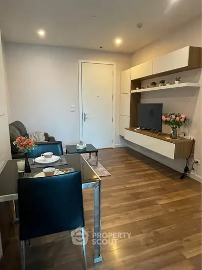 Modern living room with sleek furniture and wooden flooring, featuring a mounted TV and elegant decor.