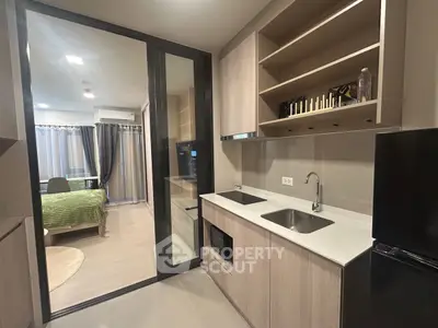 Modern kitchen with sleek cabinetry and open layout leading to a cozy bedroom.