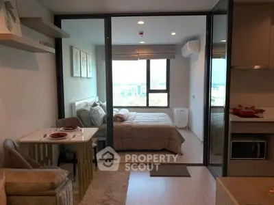 Modern studio apartment with cozy bedroom and dining area, featuring large window with city view.