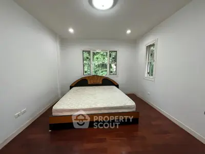 Spacious bedroom with large windows and wooden flooring