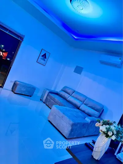 Modern living room with stylish blue lighting and plush gray sofa