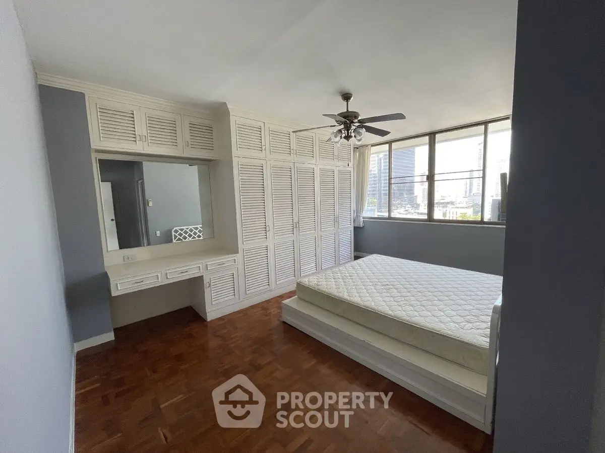 Spacious bedroom with built-in wardrobe and large windows in urban apartment