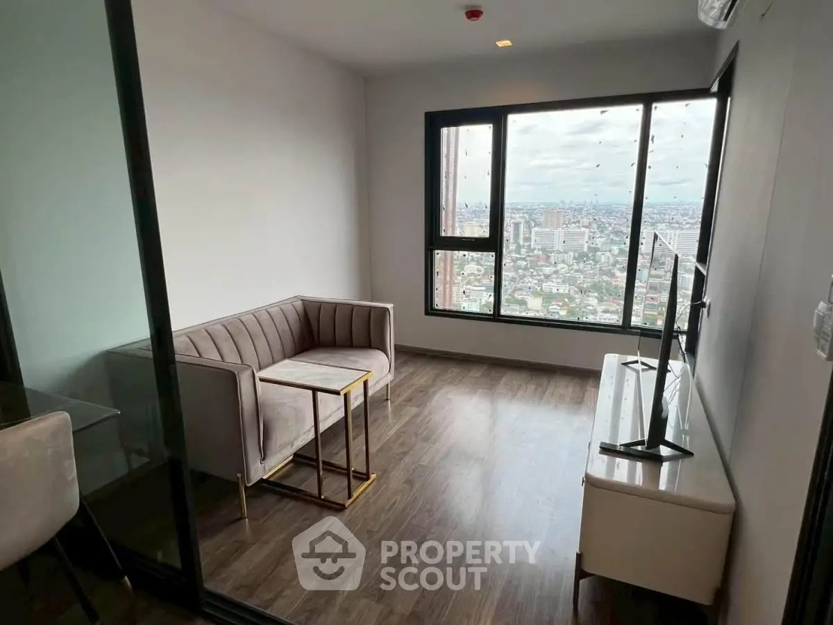 Modern living room with stunning city view, featuring sleek furniture and large windows.