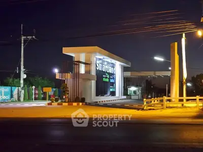 Modern real estate entrance at night with illuminated signage and sleek design.
