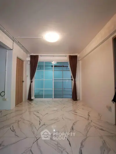 Spacious modern living room with marble flooring and large glass doors.
