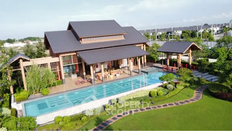 Luxurious villa with expansive pool and lush garden in serene setting.