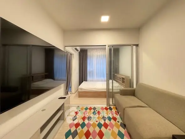 Modern living room with colorful rug and view into cozy bedroom