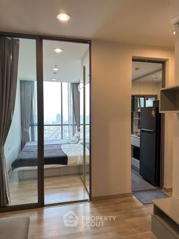 Modern apartment interior with glass-walled bedroom and city view, featuring sleek design and natural light.