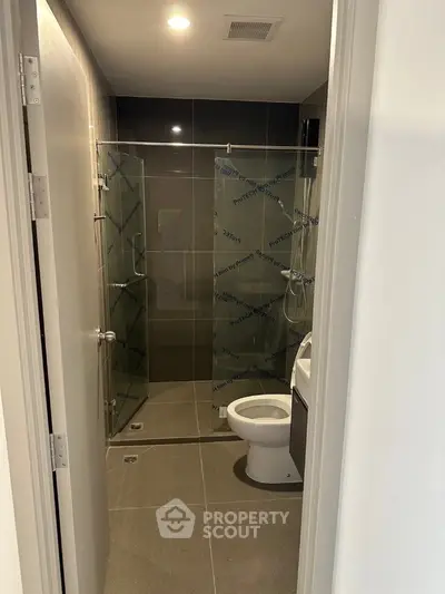 Modern bathroom with glass shower and sleek fixtures in contemporary home.