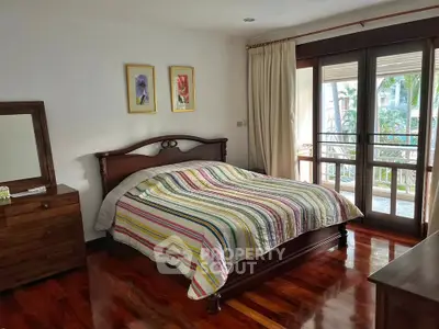Charming bedroom with wooden floors and balcony view, perfect for relaxation.