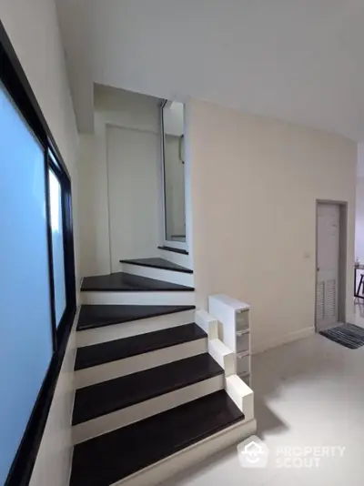 Sleek modern staircase with contrasting black and white steps in a bright, minimalist interior space, perfect for contemporary homes.