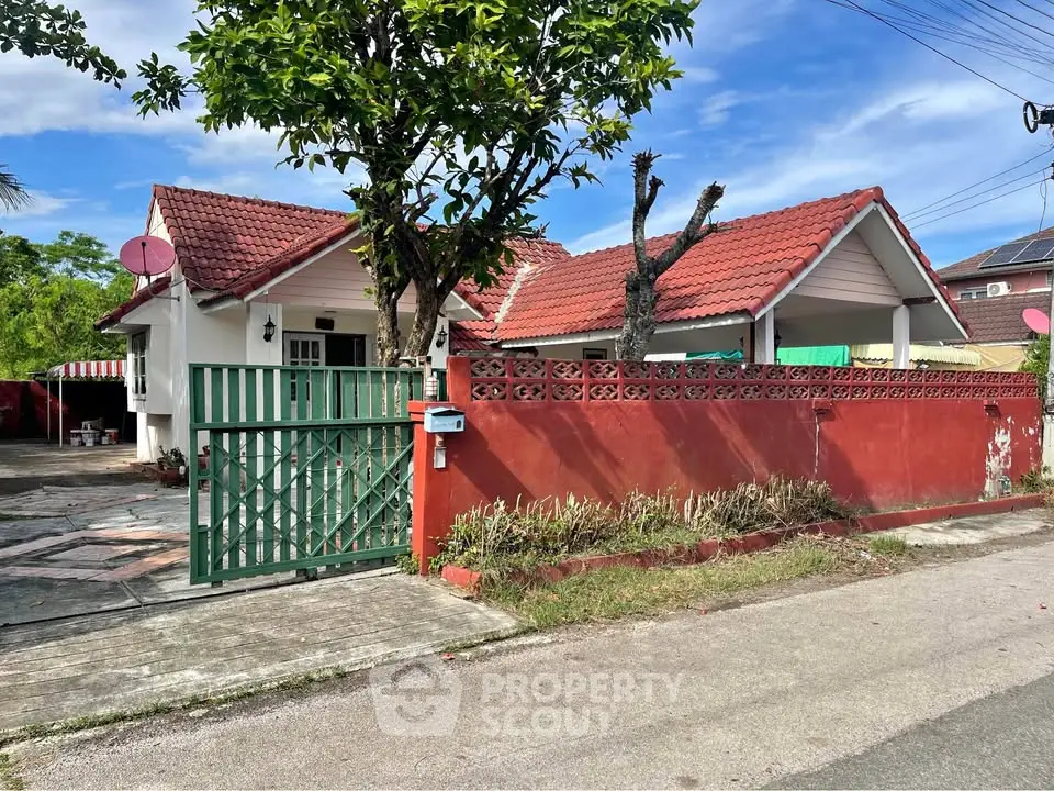 Charming single-story house with red roof and gated entrance, ideal for family living.