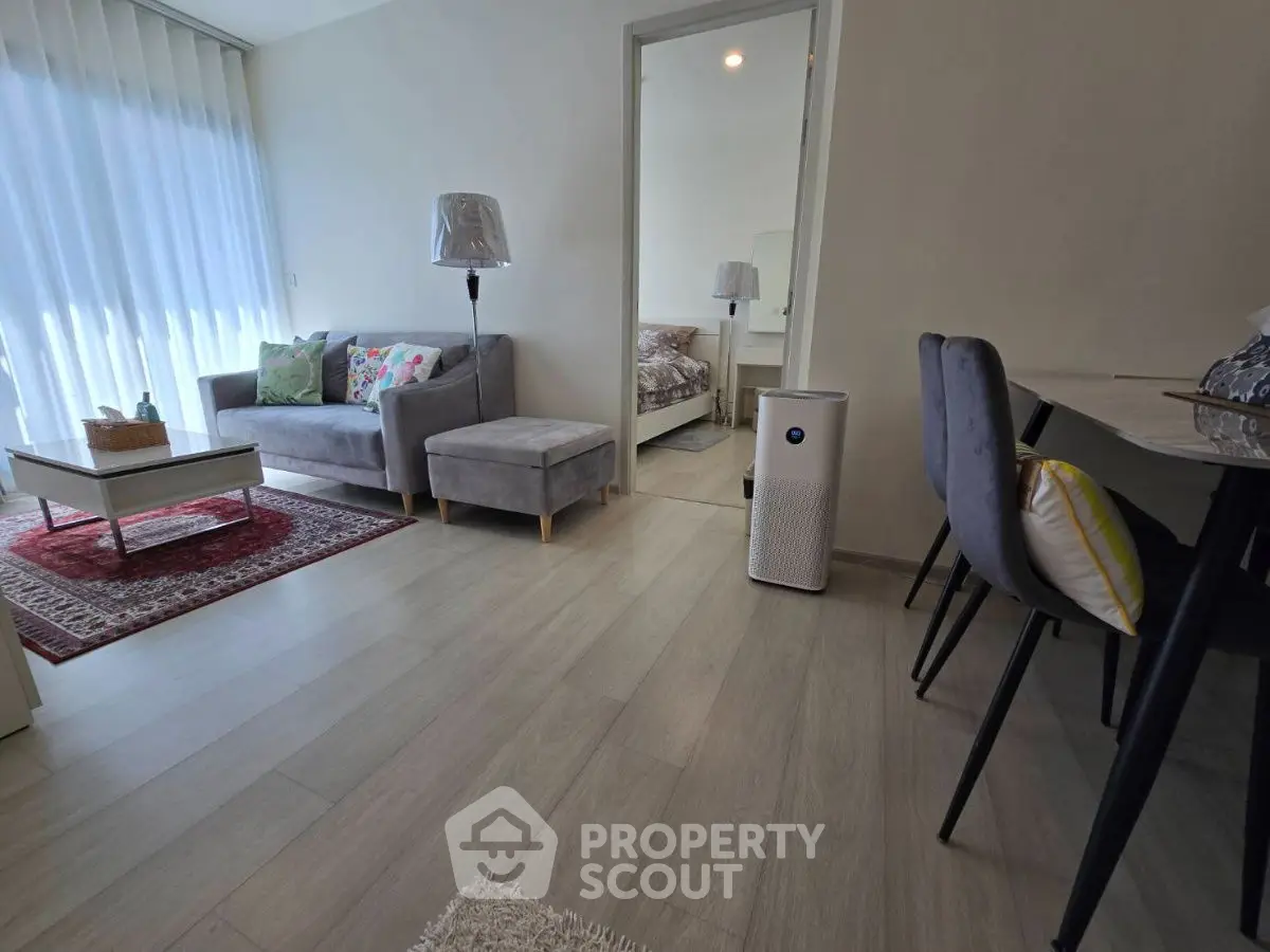 Modern living room with cozy seating and natural light, adjacent to a stylish dining area.