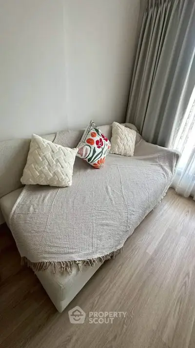 Cozy living room with stylish sofa and decorative pillows, perfect for relaxation.