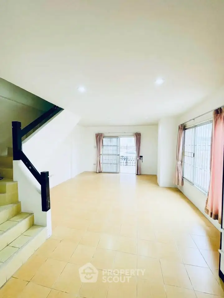 Spacious living room with large windows and staircase, ideal for family gatherings.