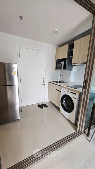 Modern compact kitchen with washing machine and sleek cabinetry in a stylish apartment.