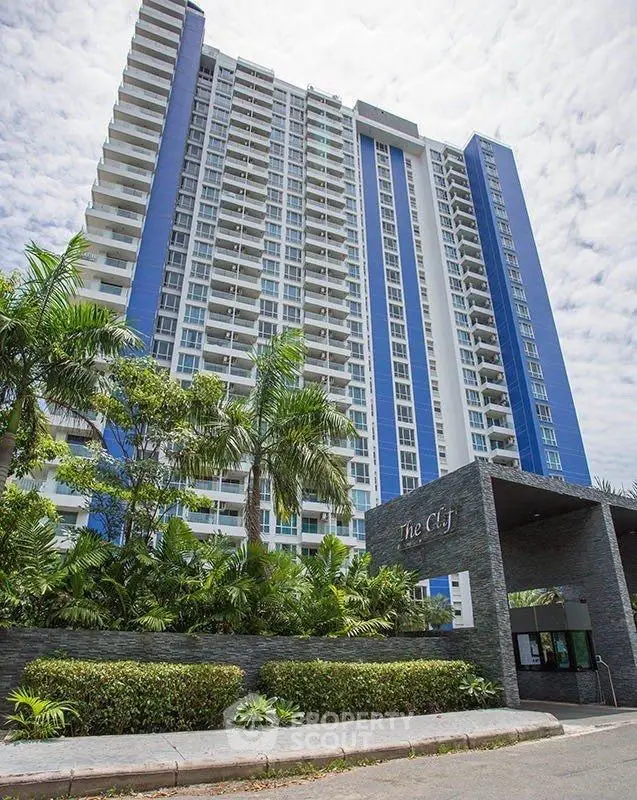 Modern high-rise building with lush greenery and elegant entrance in urban setting.