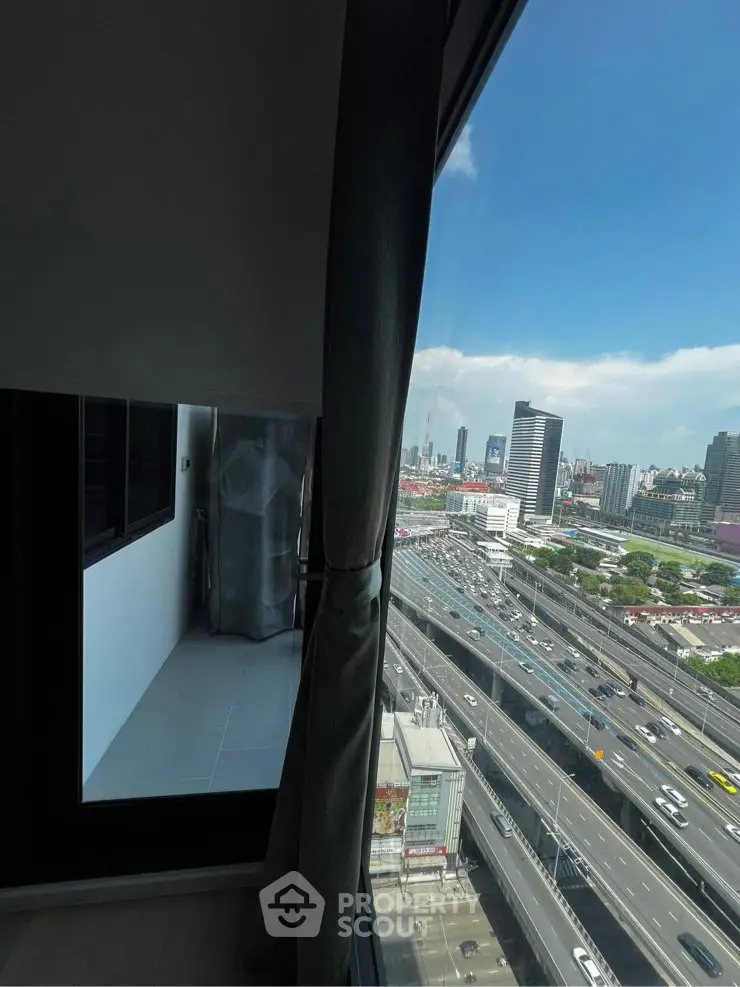 Stunning urban view from high-rise apartment window overlooking cityscape and highway.