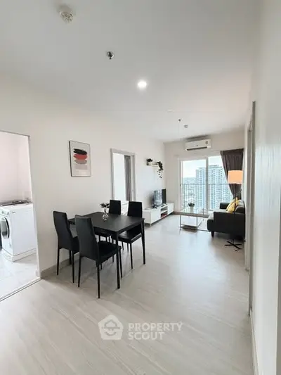 Modern living room with dining area and city view, featuring sleek furniture and bright natural light.