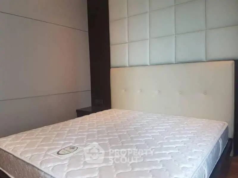 Spacious bedroom with modern padded headboard and comfortable mattress.