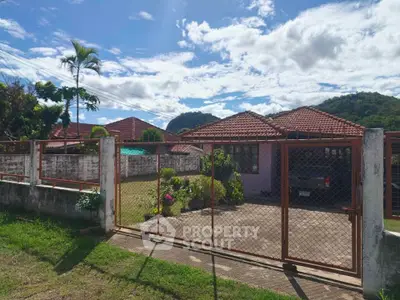 Charming suburban home with red-tiled roof and spacious front yard, perfect for family living.