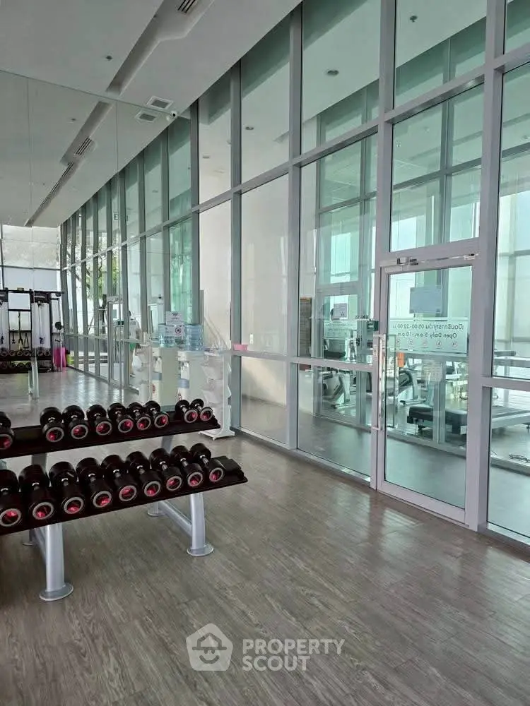 Spacious modern gym with floor-to-ceiling windows and state-of-the-art equipment.