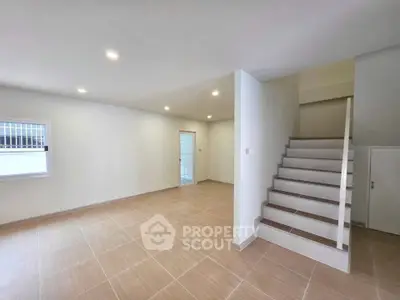 Spacious modern living room with staircase and tiled flooring in a minimalist design.