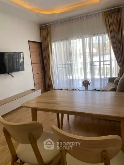 Bright living room with wooden furniture and large window view.