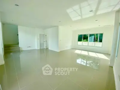 Spacious sunlit living room with glossy tiled floors and large windows