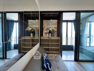 Modern living room with mirrored wall and balcony view, stylish decor and ample natural light.