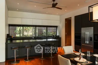 Luxurious modern kitchen with sleek black cabinetry and large windows overlooking a lush garden.