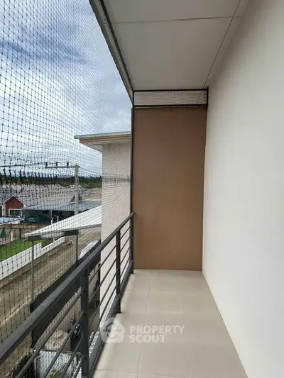 Spacious balcony with safety netting and modern railing, offering a view of the surrounding area.