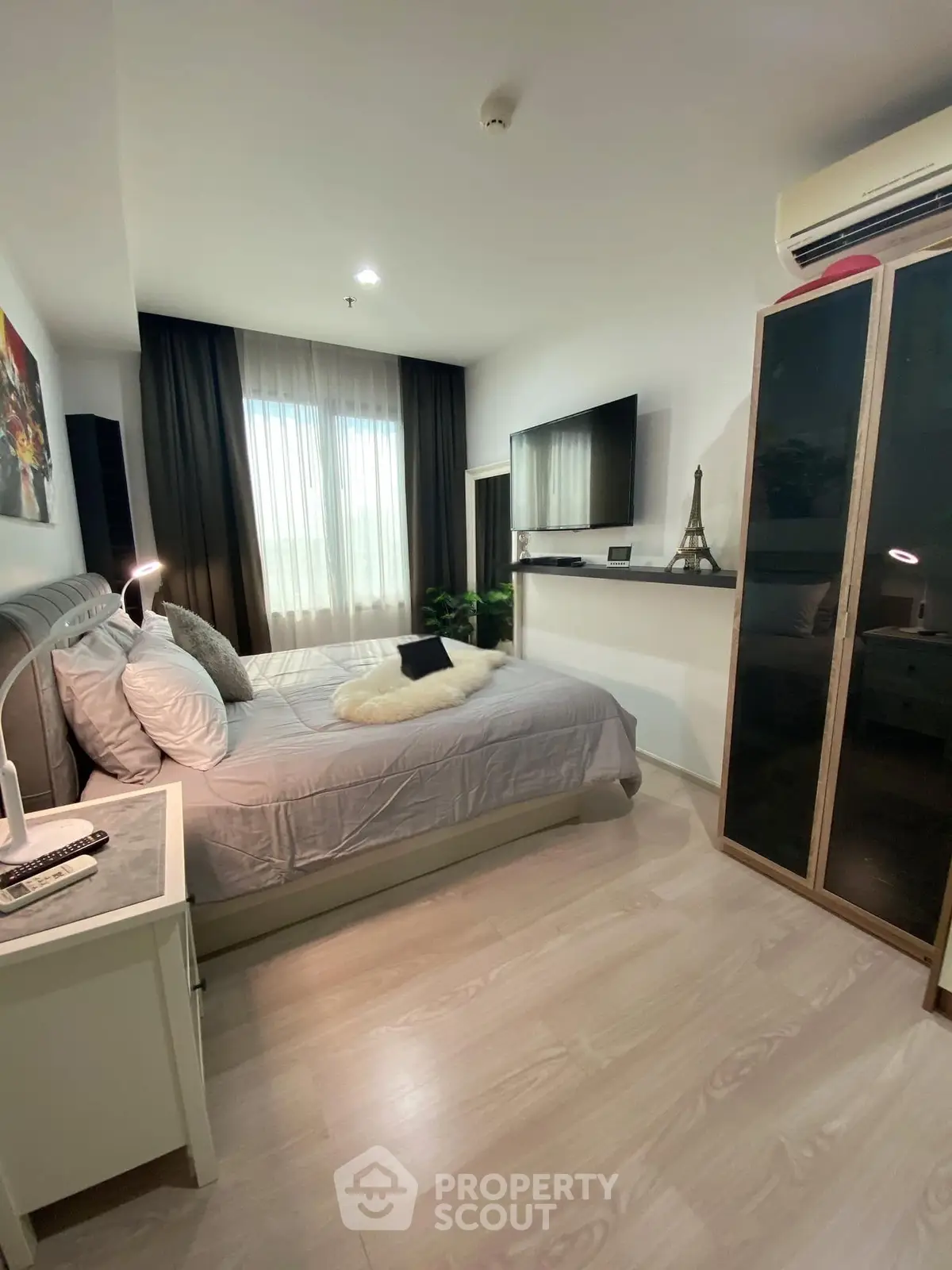 Modern bedroom with cozy decor, featuring a large bed, TV, and stylish wardrobe in a well-lit space.