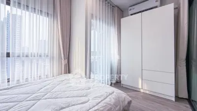 Bright modern bedroom with large windows and white wardrobe in urban apartment