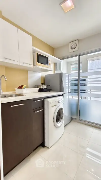 Modern kitchen with washing machine and sleek appliances in a bright, compact space.