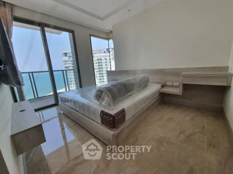 Spacious bedroom with large windows offering ample natural light and a stunning city view, featuring a modern design with sleek furniture and a polished marble floor.