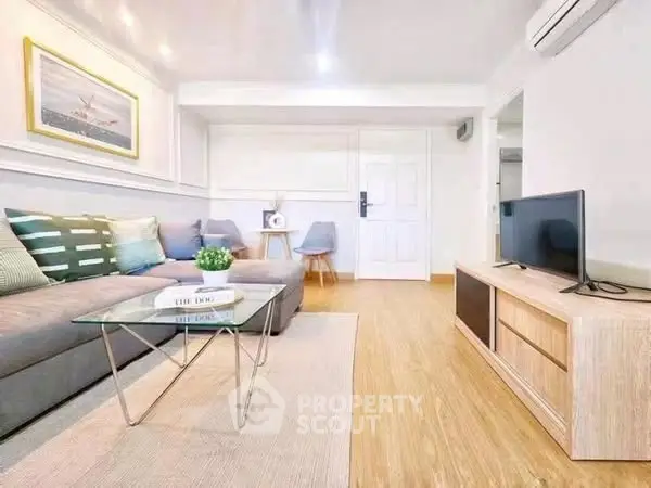 Modern living room with stylish decor and natural light, featuring a sleek TV setup and comfortable seating.