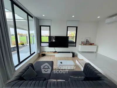 Modern living room with large windows and stylish furniture overlooking a scenic view.
