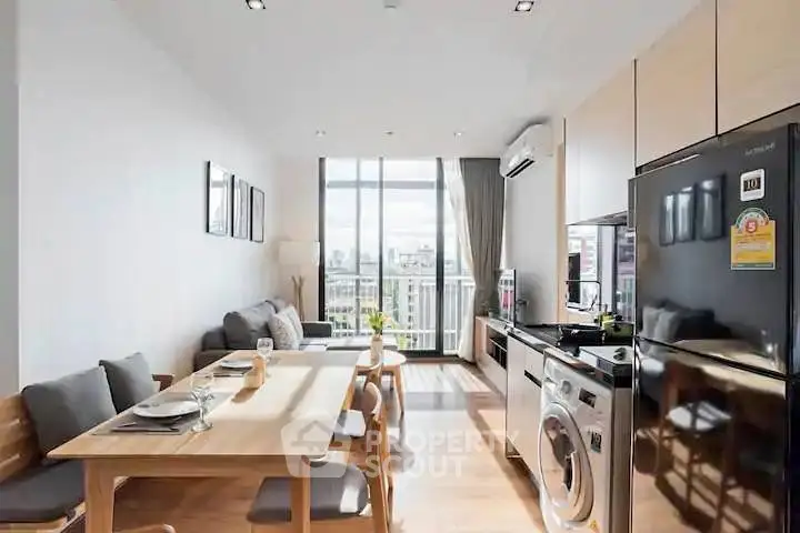 Modern open-plan living room with kitchen, featuring sleek appliances and a bright balcony view.