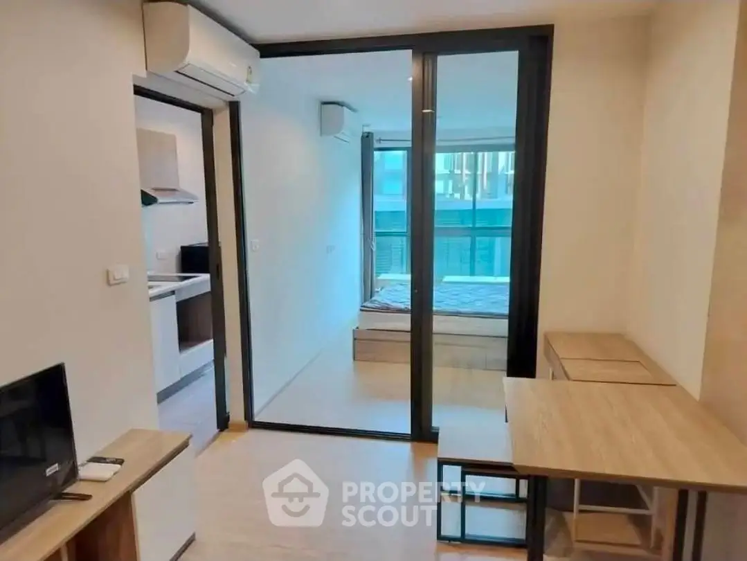 Modern apartment interior with open layout, featuring a cozy living area and a view into the bedroom.