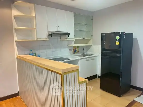 Modern kitchen with sleek cabinetry and black fridge in open layout design.