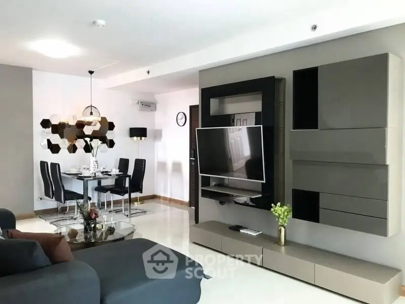 Modern living room with sleek furniture and dining area, featuring contemporary design and stylish decor.