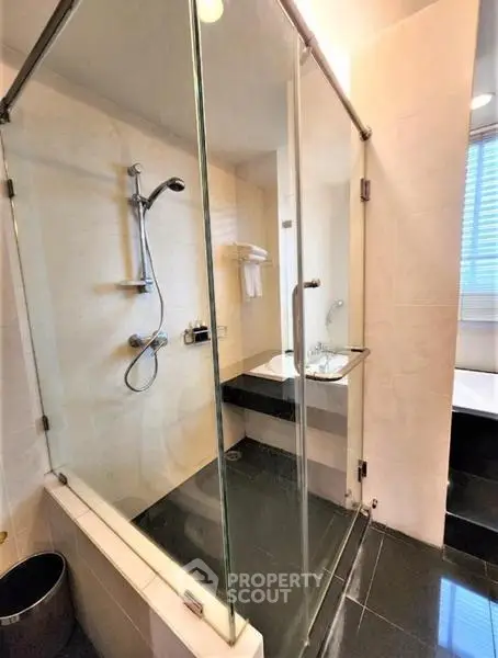Modern bathroom with glass shower enclosure and sleek black tiles