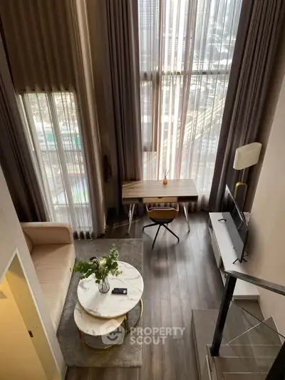 Modern loft-style living room with high ceilings and large windows, featuring elegant furniture and a cozy ambiance.