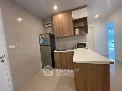 Modern kitchen with sleek cabinetry and stainless steel fridge in a cozy apartment