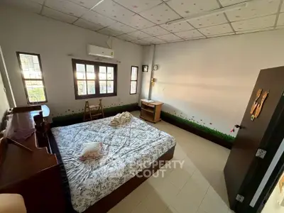 Cozy bedroom with natural light and simple decor, featuring a bed and wooden furniture.