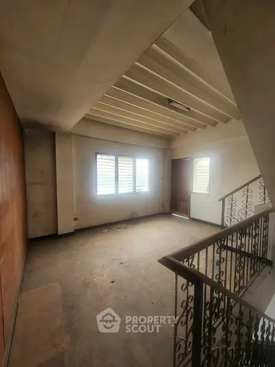 Spacious interior with natural light and elegant railing, ideal for renovation.