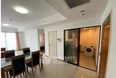 Spacious modern apartment with dining area and laundry room, featuring sleek furniture and ample natural light.