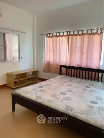 Spacious bedroom with natural light and simple furnishings, ideal for comfortable living.