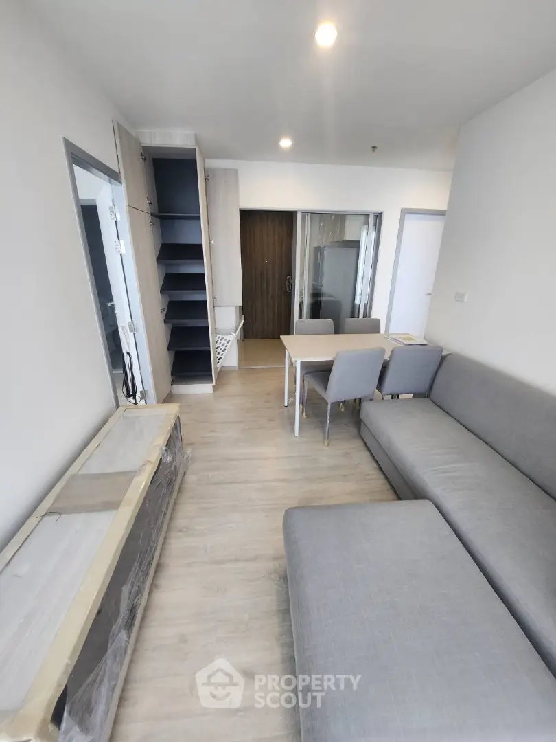 Modern living room with sleek furniture and built-in shelving, featuring a cozy gray sofa and dining area.